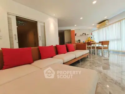 Spacious living room with modern decor and vibrant red cushions