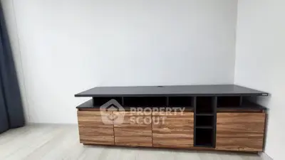 Modern wooden TV stand in minimalist living room with light wood flooring.