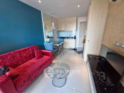 Modern living room with vibrant red sofa and sleek kitchen area, perfect for stylish urban living.