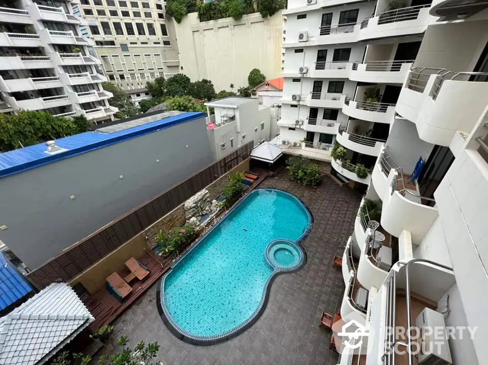 Stunning aerial view of modern apartment complex with inviting pool and lush greenery.