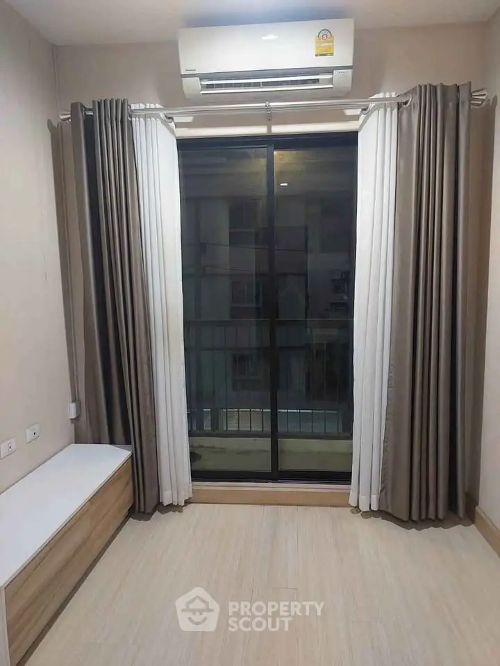 Modern room with large window and air conditioning, featuring elegant curtains and wooden flooring.
