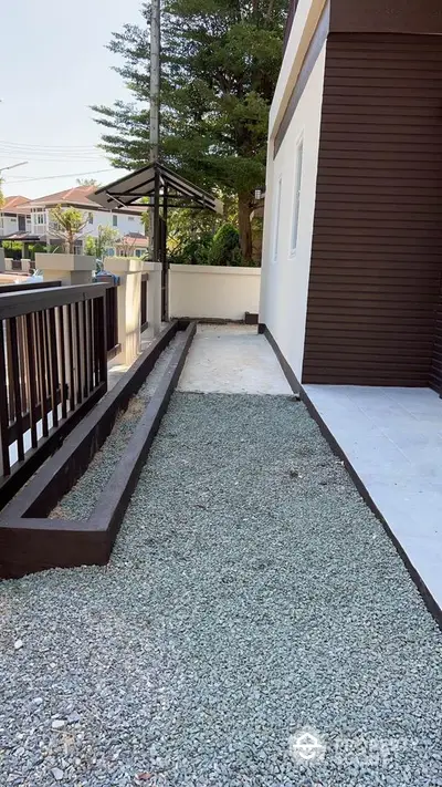 Modern residential exterior with gravel pathway and sleek fencing