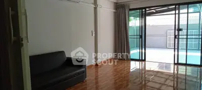 Spacious living room with sliding glass doors leading to a private patio, featuring sleek flooring and modern decor.