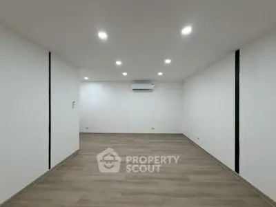 Spacious empty room with modern lighting and wooden flooring, ideal for customization.