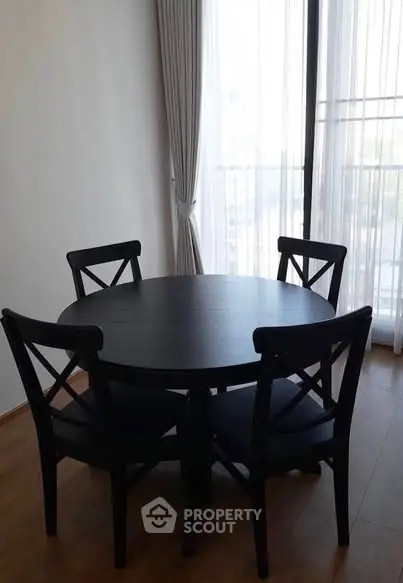 Cozy dining area with round table and chairs by a sunlit window.