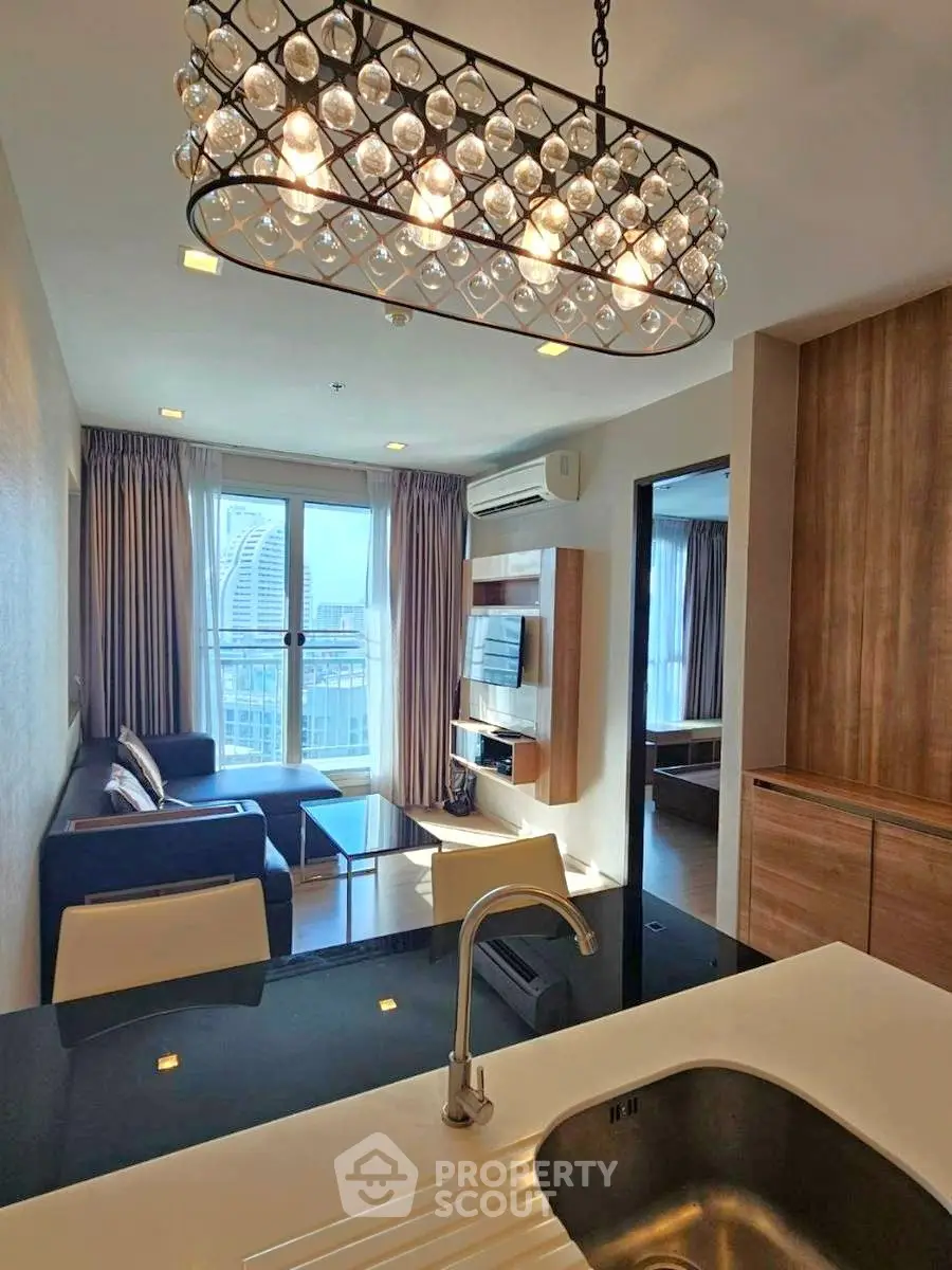 Modern living room with elegant chandelier and city view from balcony.