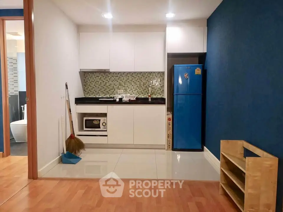 Modern compact kitchen with blue fridge and sleek cabinetry in cozy apartment.