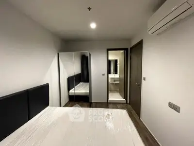 Modern bedroom with mirrored wardrobe and ensuite bathroom in stylish apartment.