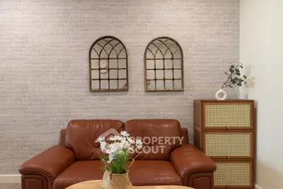 Stylish living room with leather sofa, decorative wall mirrors, and modern storage unit.