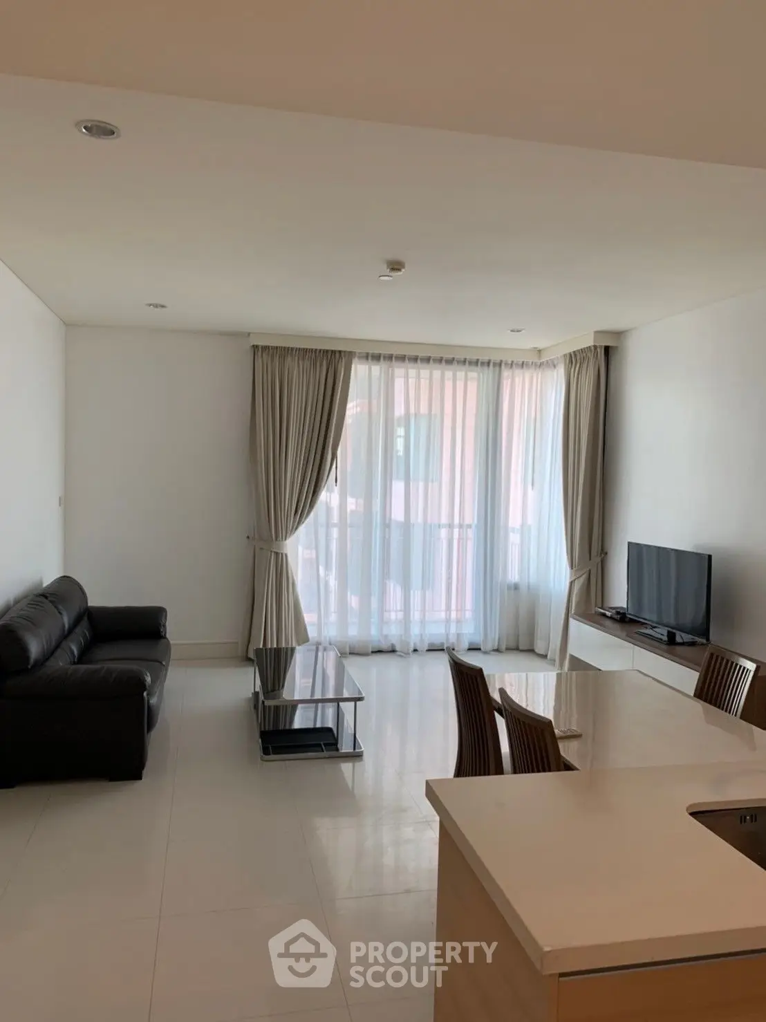 Spacious and well-lit living room with modern furnishings, sleek tiled flooring, and large windows draped with elegant curtains, perfect for comfortable urban living.