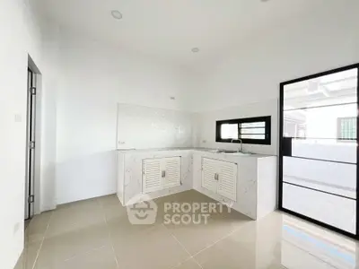 Modern minimalist kitchen with sleek white cabinetry and large window