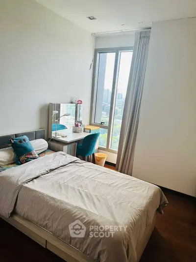Cozy bedroom with city view, featuring a single bed and study desk by the window.