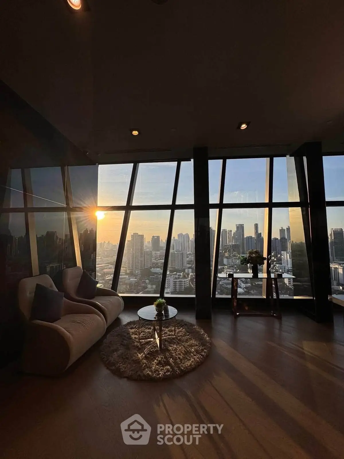 Luxurious living room with panoramic city view and elegant furnishings at sunset.