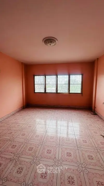 Spacious empty room with tiled floor and large windows in a real estate property.