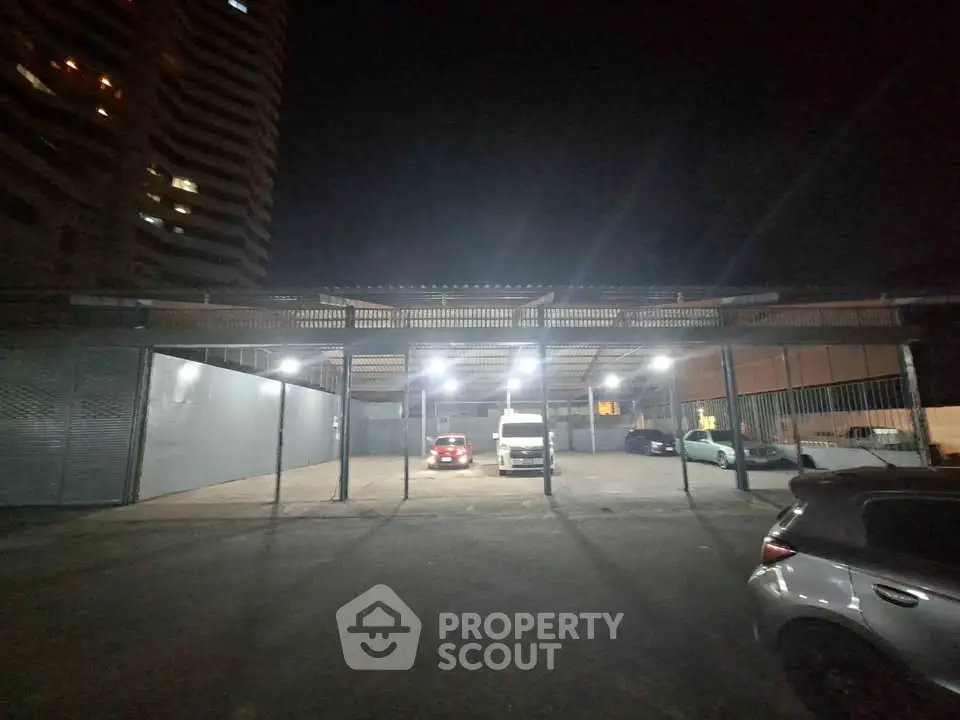 Spacious parking area with multiple vehicles under bright lights at night.