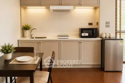 Modern kitchen with sleek cabinetry and dining area, featuring a compact fridge and microwave.