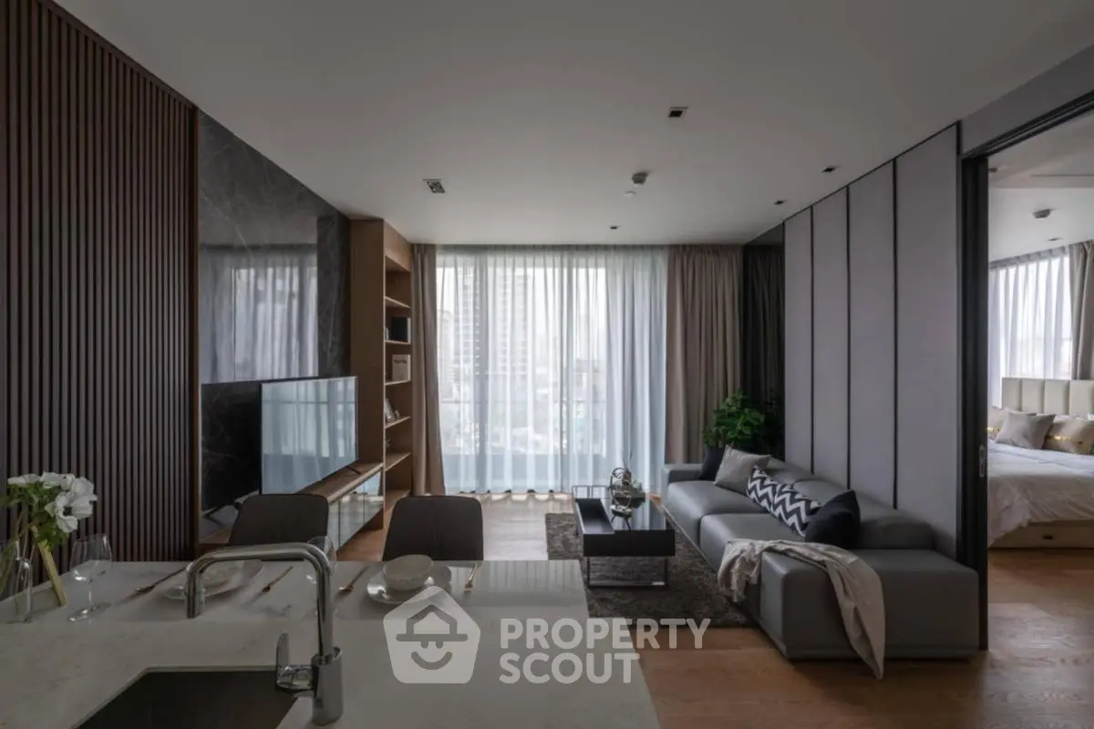 Modern living room with open kitchen, stylish decor, and large windows offering city views.