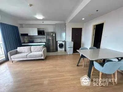 Modern open-plan living room with kitchen, featuring a washing machine and stylish furniture.