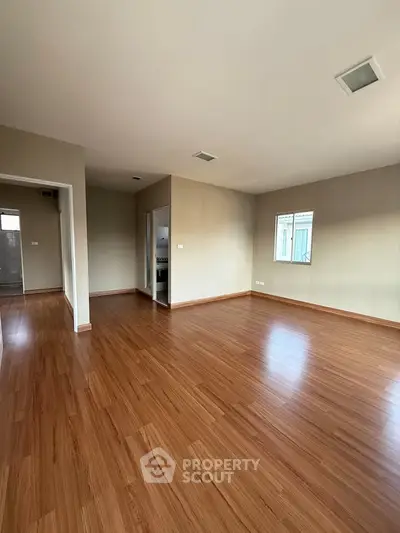 Spacious empty room with wooden flooring and natural light, ideal for customization.