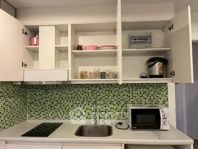 Modern kitchen with open cabinets, green mosaic backsplash, and sleek appliances.