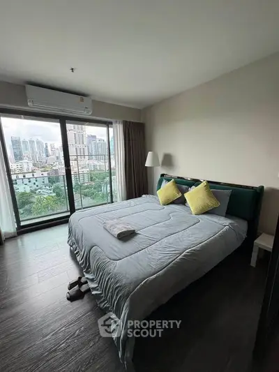 Modern bedroom with city view, featuring large windows and stylish decor.