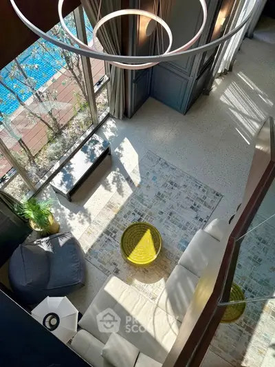 Luxurious living room with high ceiling and pool view, featuring modern furniture and elegant decor.