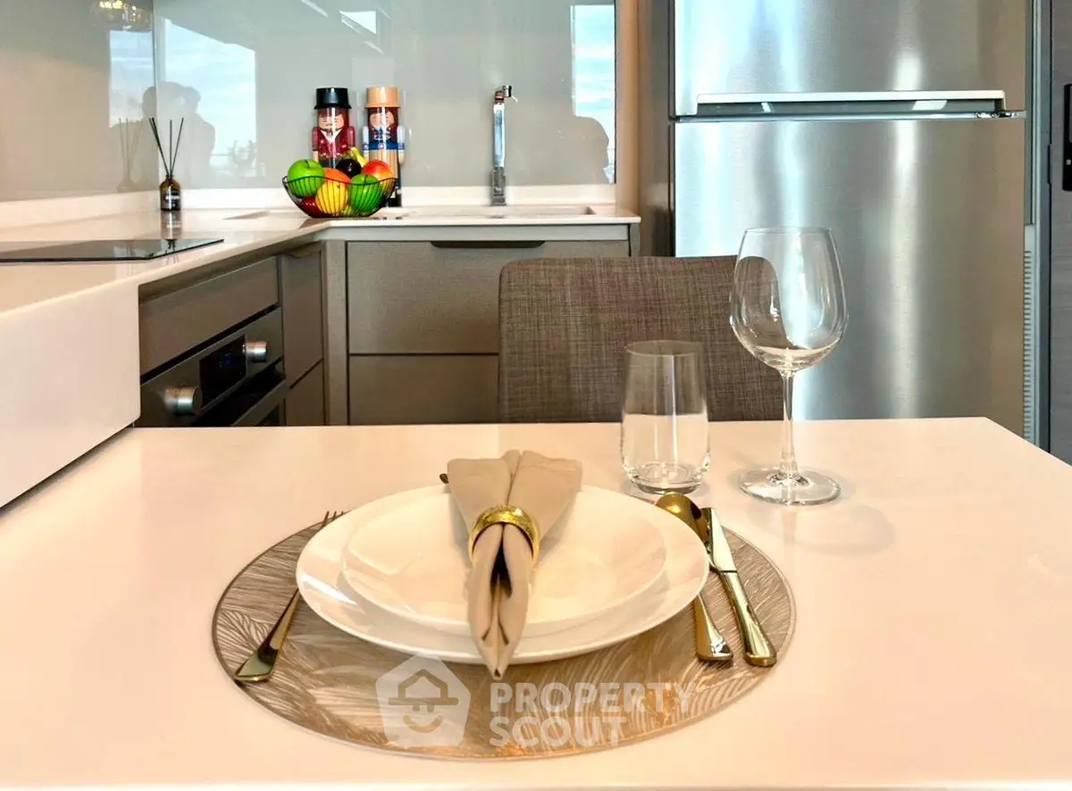 Modern kitchen with sleek appliances and elegant dining setup, featuring a stainless steel fridge and stylish decor.