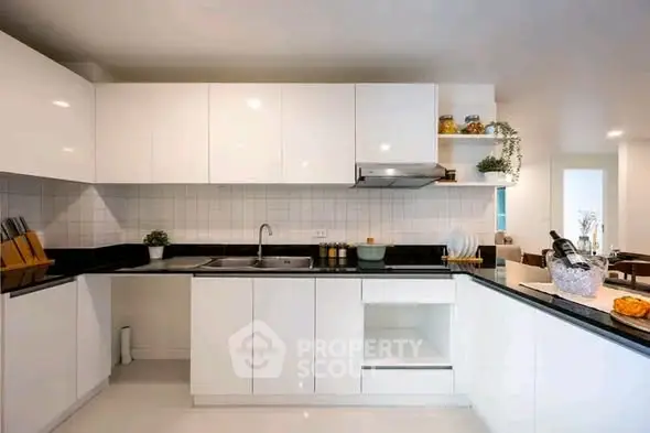Modern kitchen with sleek white cabinets and black countertops in a stylish open layout.