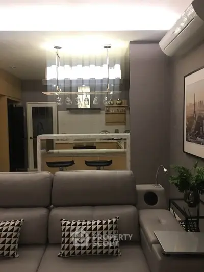 Modern living room with stylish decor and open kitchen layout, featuring sleek furniture and elegant lighting.
