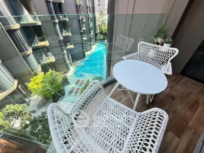 Luxurious balcony with wicker furniture overlooking a stunning pool view in a modern apartment complex.
