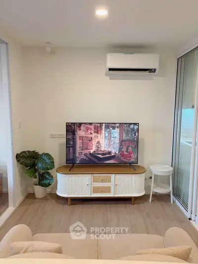 Modern living room with stylish TV stand and air conditioning, featuring cozy decor and natural light.