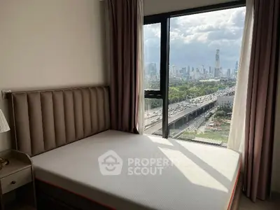 Modern bedroom with city view from large window, featuring stylish bed and nightstand.