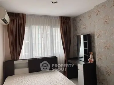 Cozy bedroom with elegant wallpaper and natural light, featuring a stylish vanity and comfortable bed.