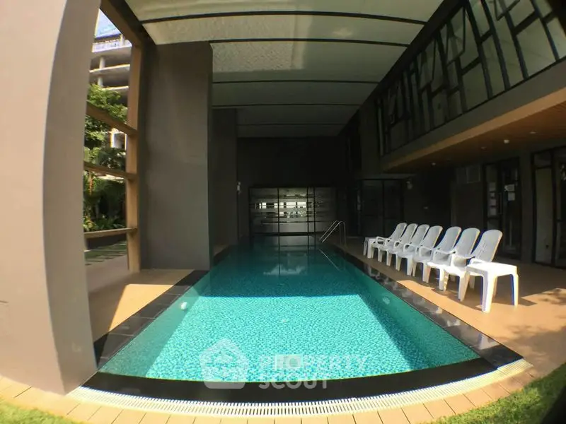 Luxurious indoor pool area with modern design and ample seating in a high-end residential complex.
