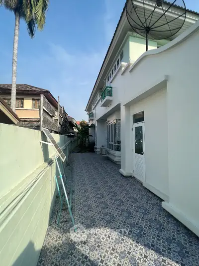 Charming exterior view of a spacious residential property with tiled pathway and satellite dish.