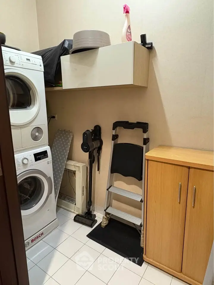 Compact laundry room with Bosch washer and dryer, storage cabinets, and cleaning tools.