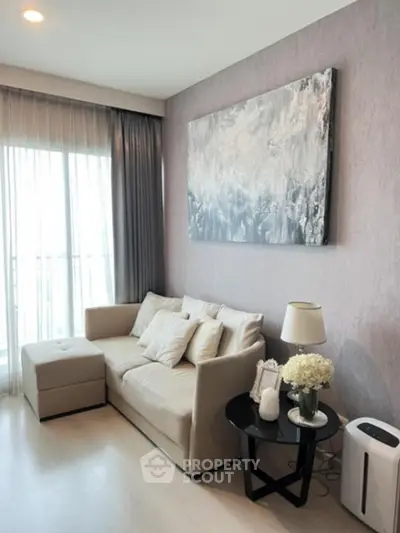 Elegant living room with a plush beige sofa set, modern art piece on the wall, and tasteful decor creating a warm, inviting atmosphere for relaxation and socializing.
