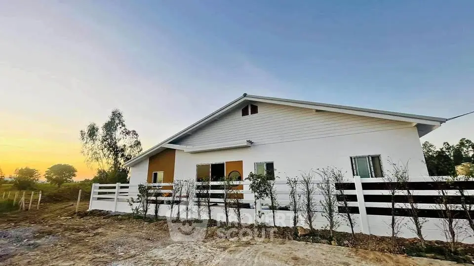 Charming modern house with white exterior and lush garden at sunset