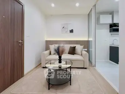 Modern living room with cozy sofa and stylish decor adjacent to sleek kitchen.