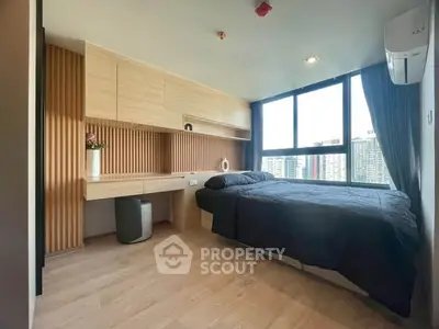 Modern bedroom with large window and built-in desk, offering city views and ample natural light.