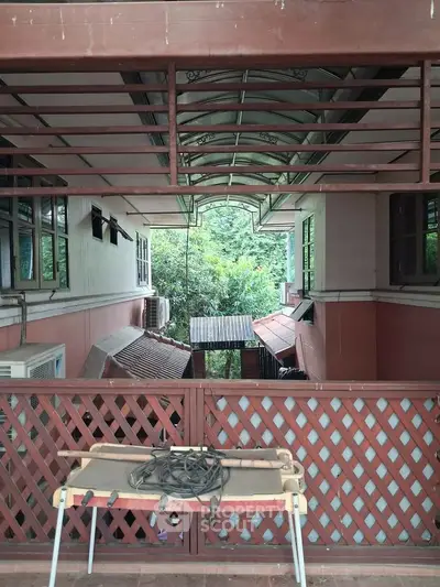 Charming balcony view with rustic lattice railing and lush greenery in a serene residential setting.
