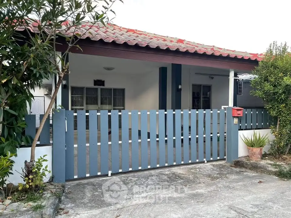 Charming single-story home with a red-tiled roof and spacious front yard.