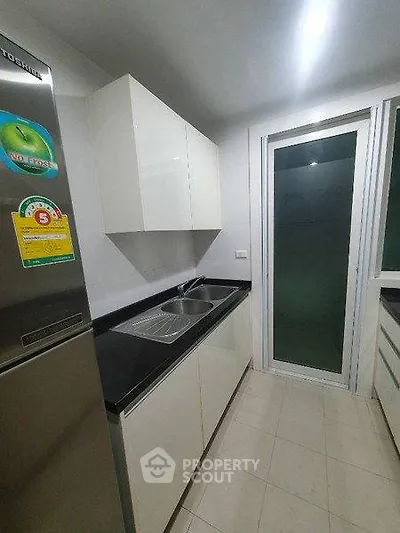 Modern kitchen with sleek cabinetry and stainless steel fridge in a compact layout.
