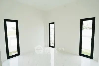 Bright minimalist room with large windows and white tiled floor, perfect for modern living.