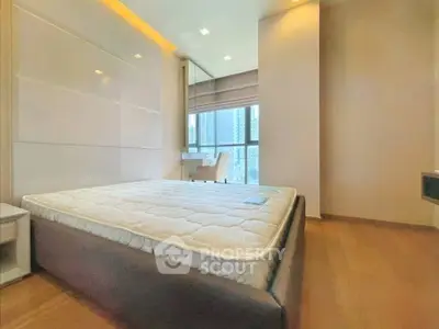Spacious bedroom with large window and modern furnishings in a high-rise apartment.