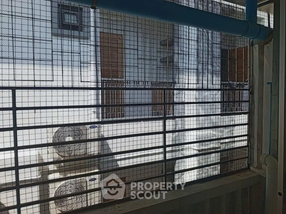 View of building exterior with air conditioning units and safety grills