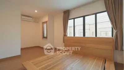 Spacious bedroom with wooden flooring and large windows in modern home.