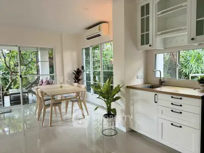Bright kitchen and dining area with garden view and modern furnishings.