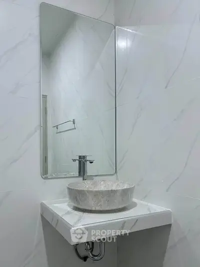 Modern minimalist bathroom with elegant marble sink and sleek mirror design.