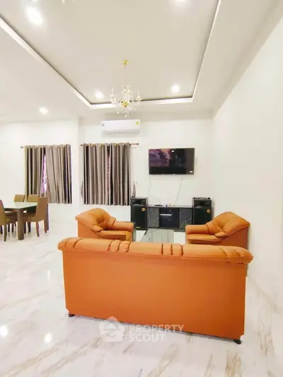 Elegant living room with modern decor, featuring plush orange sofas and a wall-mounted TV.